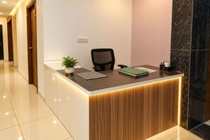 Un mostrador de recepción con una planta, una silla y un libro.