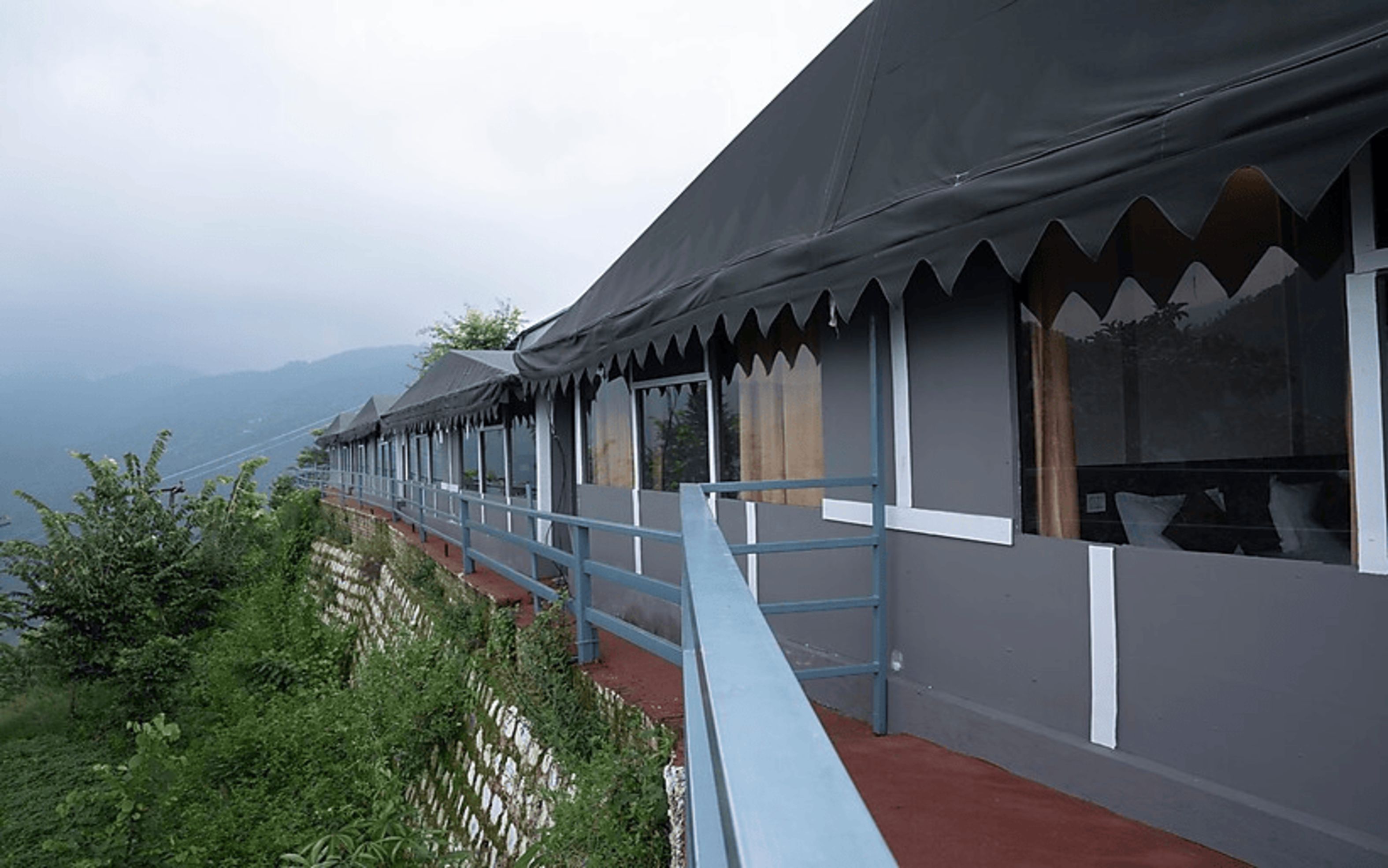 Una hilera de habitaciones con balcón, barandilla y vistas a las montañas.