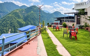 A hotel with outdoor seating and a view of mountains. - Thavika River Retreat - Dehradun (Dehradun)