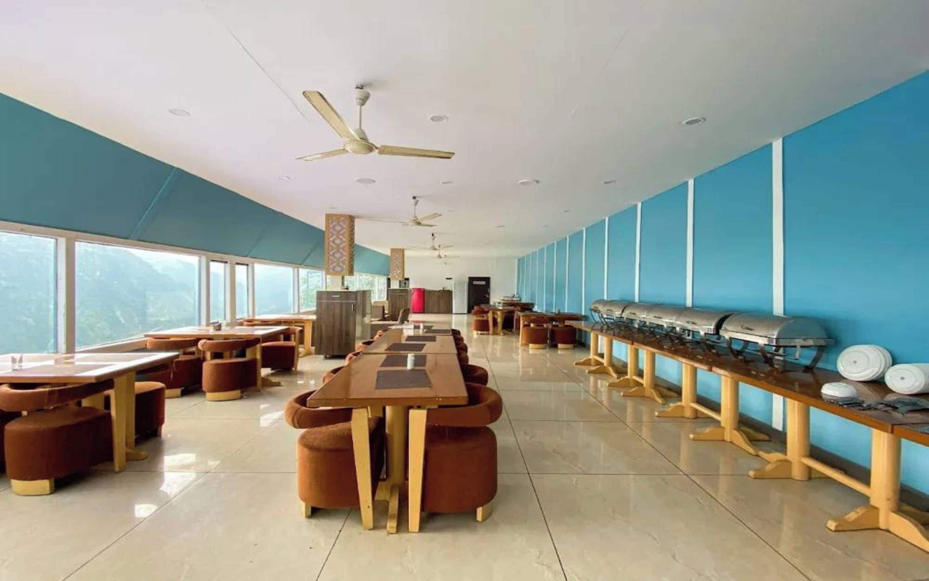 A spacious dining area with high tables and chairs, a buffet line, and a view of the outdoors.