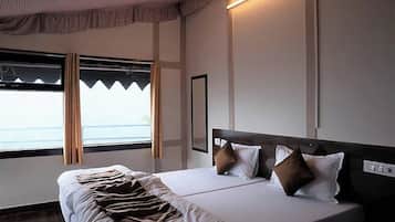 Habitación de hotel con cama, ventana con cortinas, lámpara de pared y espejo.