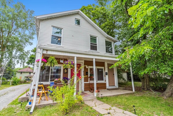 A two-story house with a porch, a front door, and a mailbox.