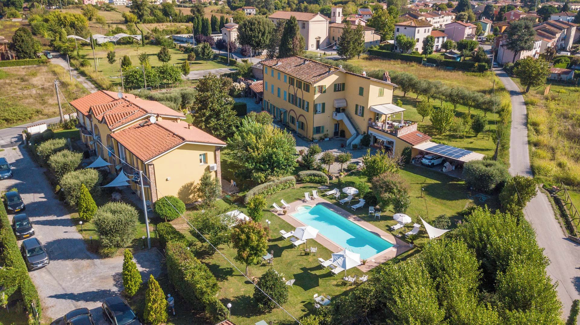 A residential property with a swimming pool, a covered patio, and a well-maintained garden.