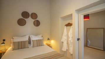 Una camera da letto con un letto, due lampade sui comodini, uno specchio a parete e una porta che dà su un bagno.