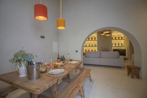 A dining area with a wooden table set for a meal, a sofa, and a TV in the background.