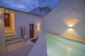 Un edificio moderno con una escalera, una piscina e iluminación exterior.