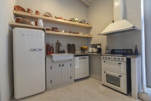 Eine kleine Küche mit einem weißen Kühlschrank, einer Spüle und einem Herd.