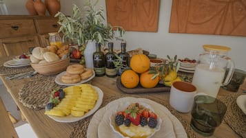 Una tavola imbandita per la colazione, con frutta, dolci e bevande.