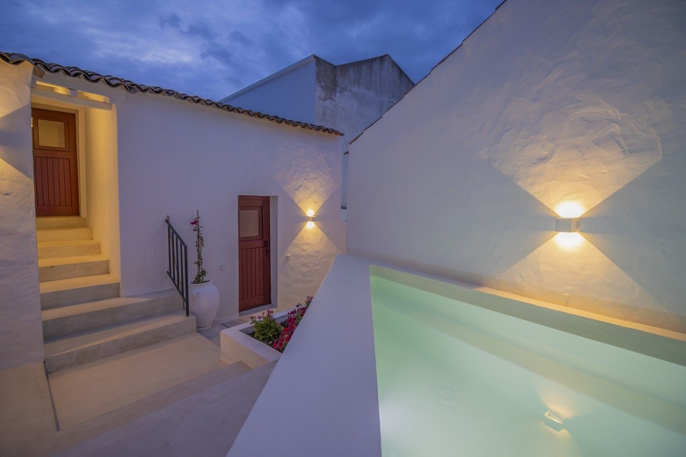 A modern building with a staircase, a pool, and exterior lighting.