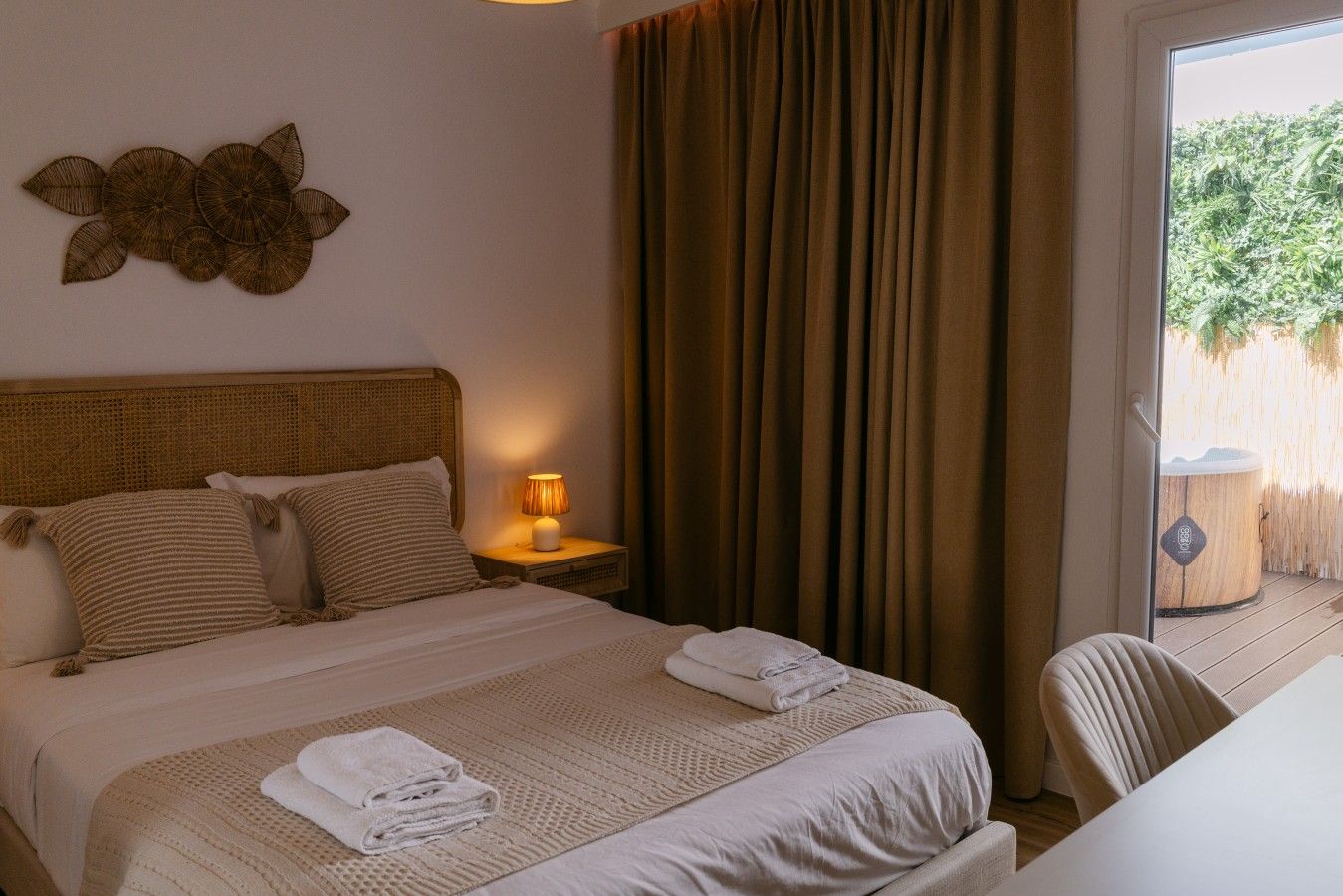 Habitació d'hotel amb llit, una petita taula de nit amb una làmpada, una finestra amb cortines i vista a l'exterior.