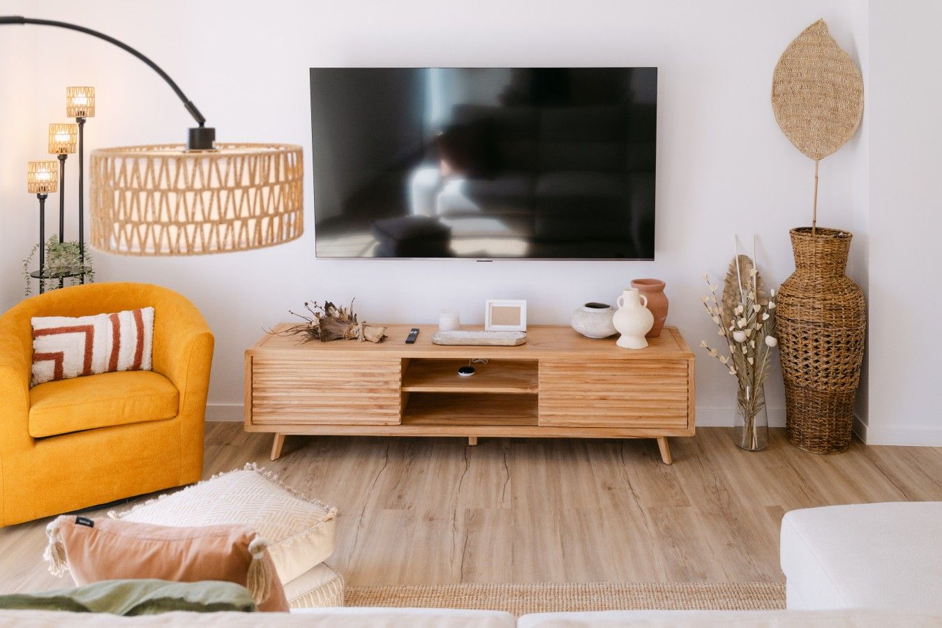Un saló modern amb un televisió de pantalla plana gran, una taula de palanca de fusta, un butac armchair groc i un ramader trenat.