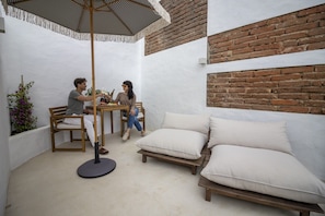 Un patio con mesa y sillas, un banco de madera y un sofá acolchado.