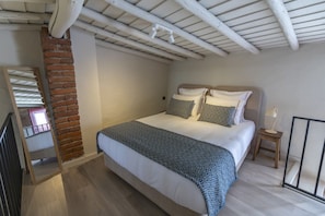Ein Schlafzimmer mit einem Bett, einem Nachttisch, einer Lampe, einem Spiegel und einer Ziegelwand.