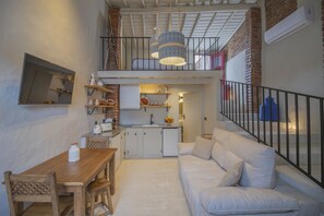 Un espacio habitable compacto con comedor, kitchenette y sofá.