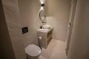 Un baño pequeño y moderno con inodoro, lavabo y espejo.