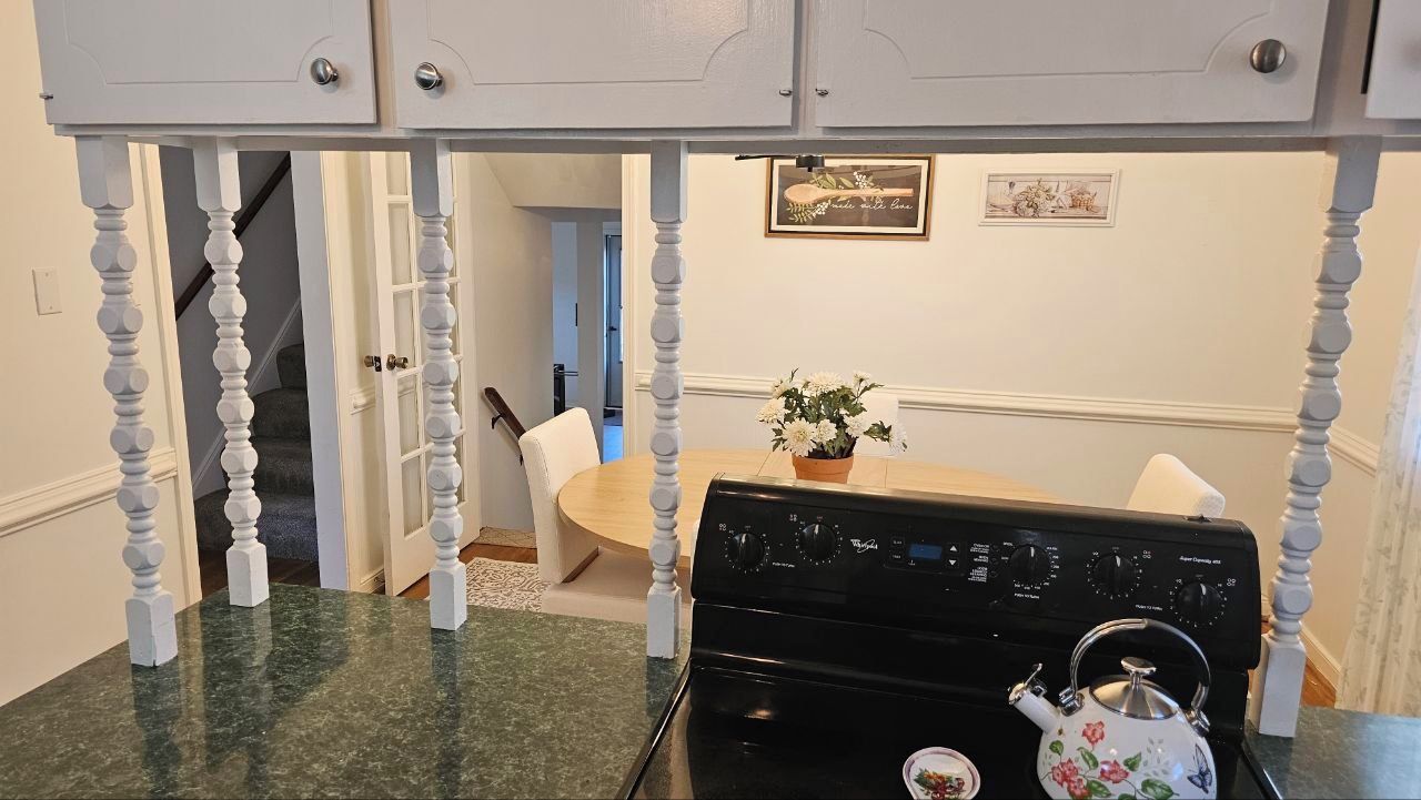 A kitchen with a black stove, a white cabinet above, and a dining table with chairs.