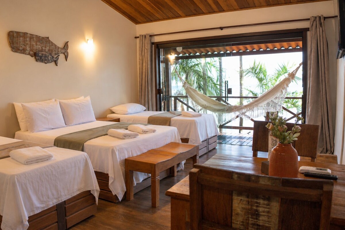 Une chambre d’hôtel avec deux lits, un hamac, une table en bois et une vue sur les palmiers.