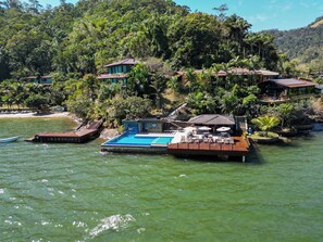 Une structure flottante dotée d’une piscine, entourée d’une végétation luxuriante et de collines.