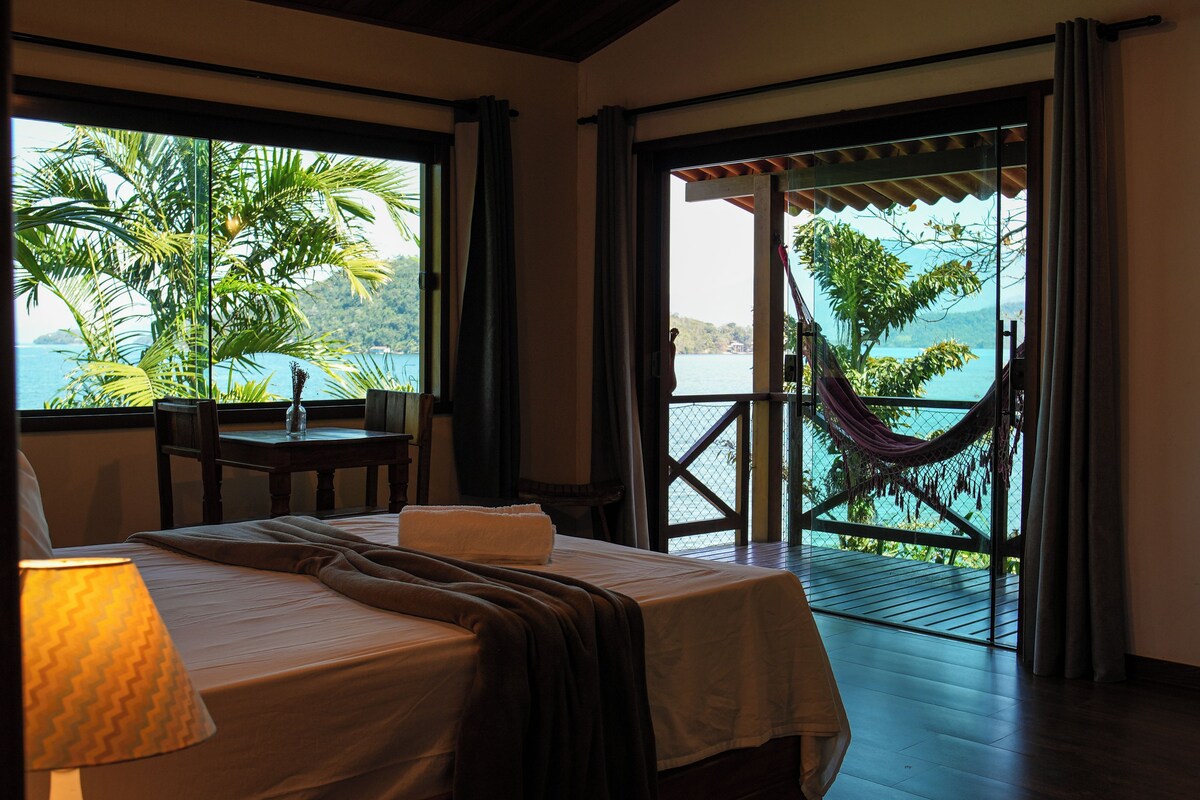 Une chambre d’hôtel avec un lit, une table et vue sur la mer.