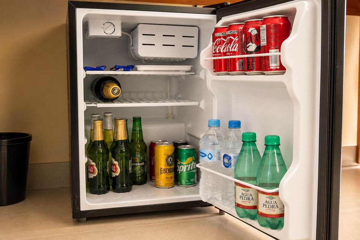 Un réfrigérateur ouvert contenant diverses boissons, notamment de la bière, des sodas et de l’eau.