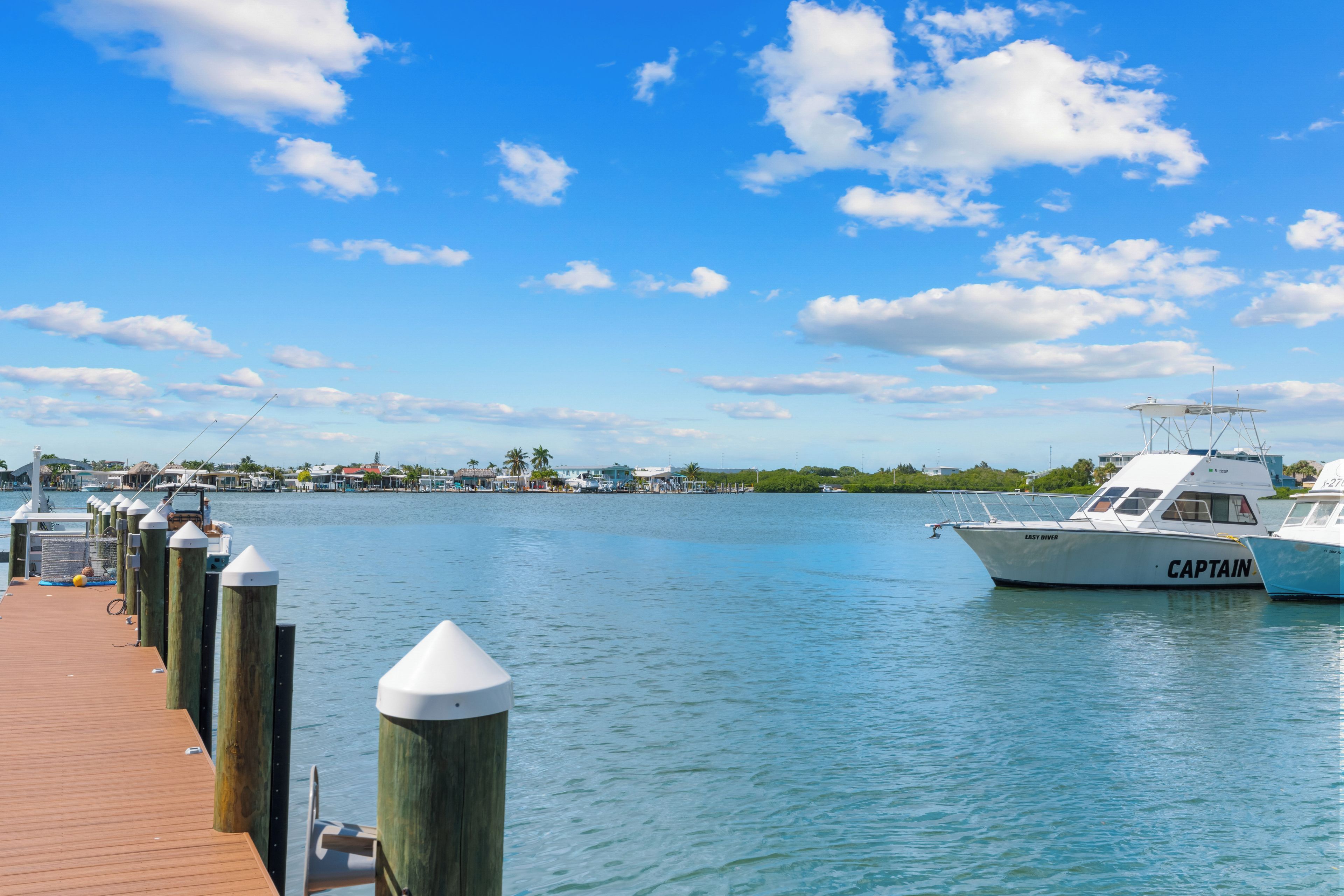A marina with boats docked, a wooden pier, and a clear blue sky.