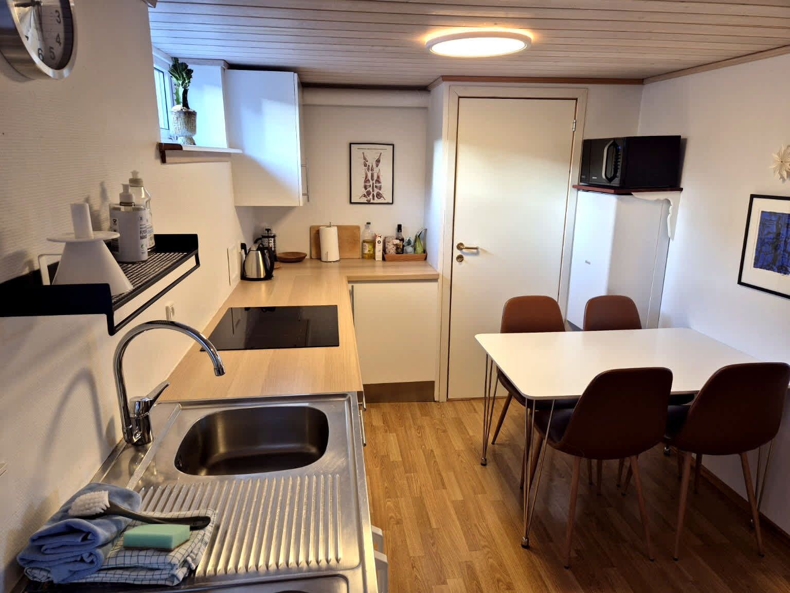 Une cuisine compacte équipée d’un évier, d’une cuisinière et d’un four à micro-ondes. Un coin repas avec une table et des chaises est également disponible.