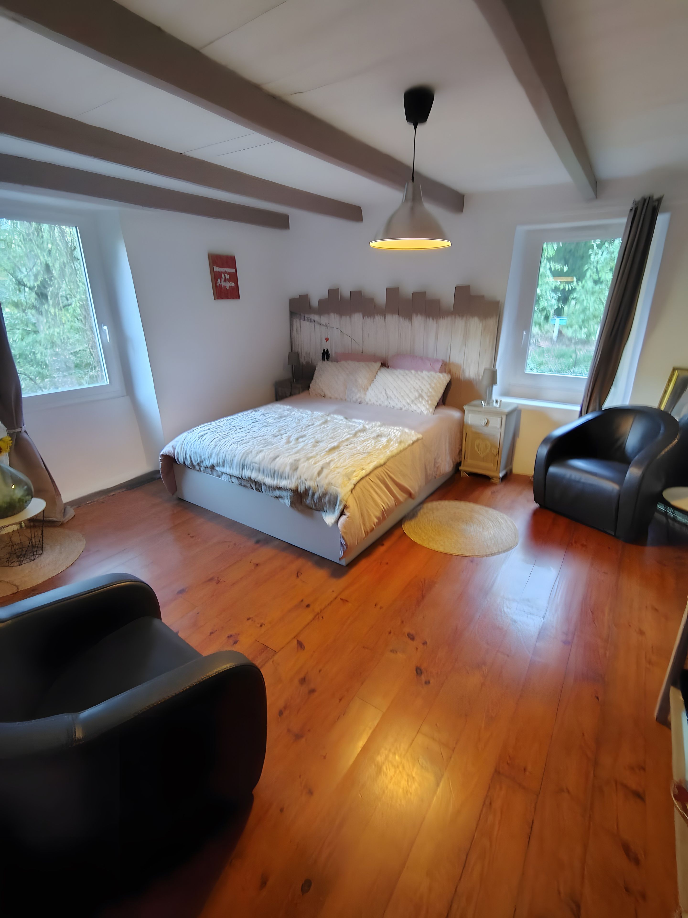 Ein Schlafzimmer mit einem Bett, einem Deckenventilator, einem Fenster und einem schwarzen Ledersessel.