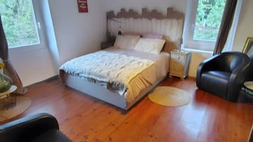Ein Schlafzimmer mit einem Bett, einem Deckenventilator, einem Fenster und einem schwarzen Ledersessel.