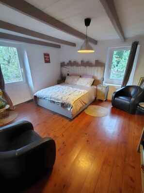 Ein Schlafzimmer mit einem Bett, einem Deckenventilator, einem Fenster und einem schwarzen Ledersessel.