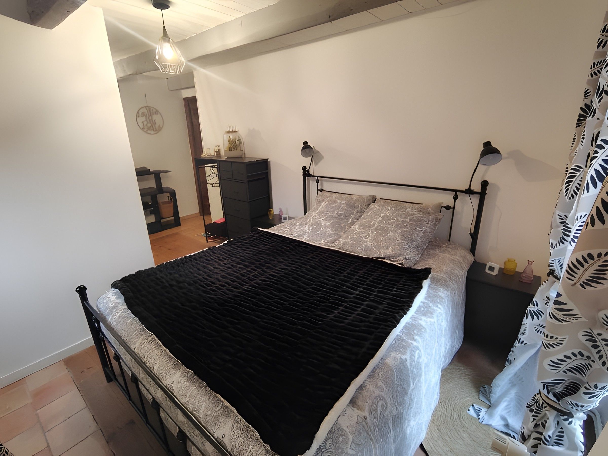 Un dormitorio con cama, mesitas de noche, armario e iluminación colgante.