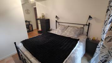 Un dormitorio con cama, mesitas de noche, armario e iluminación colgante.