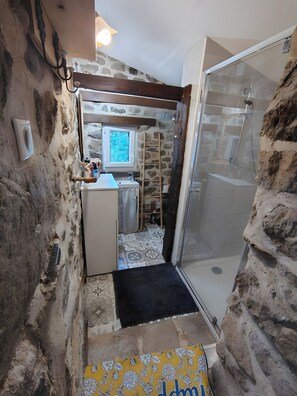 Ein kleines Badezimmer mit Dusche, Fenster und Spüle.