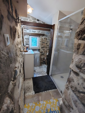 Ein kleines Badezimmer mit Dusche, Fenster und Spüle.