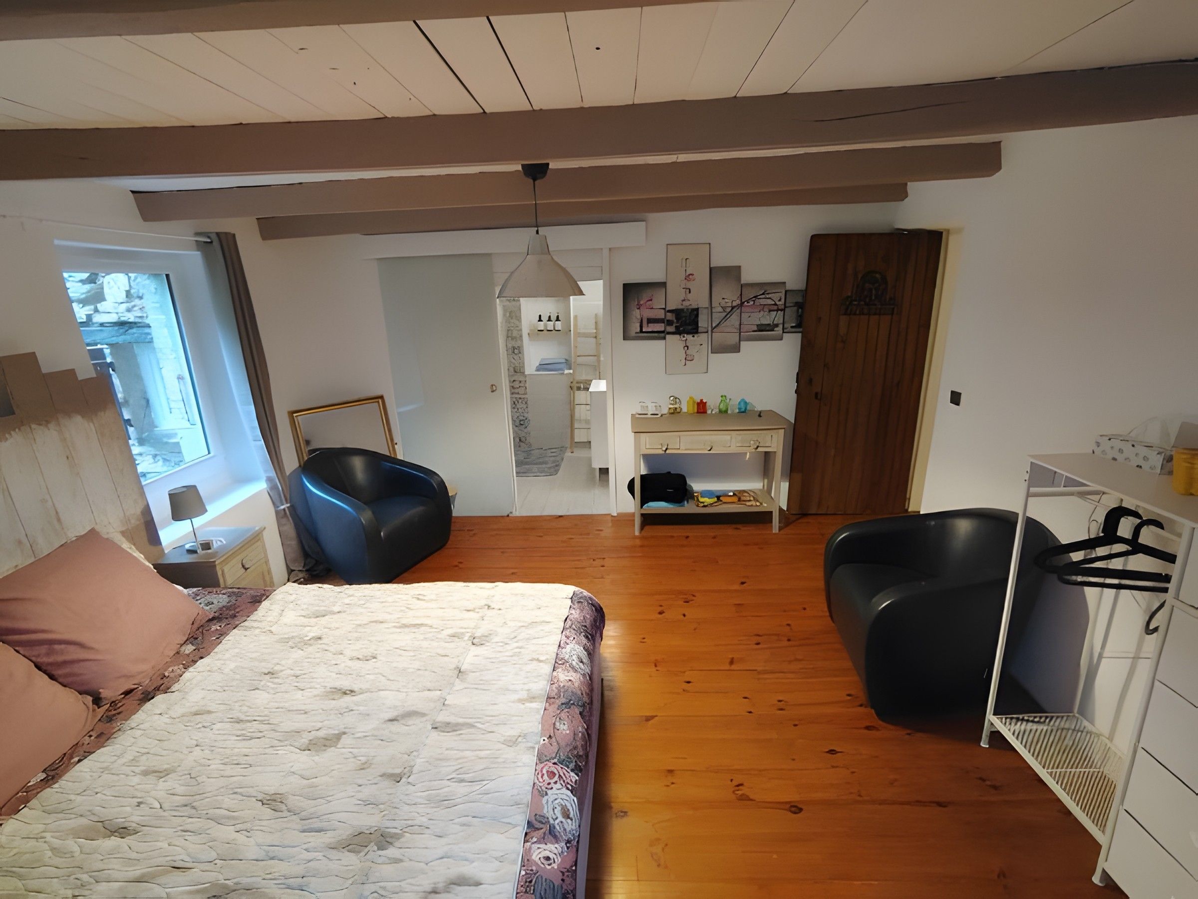 Een slaapkamer met een bed, twee stoelen, een bureau en een kledingkast.