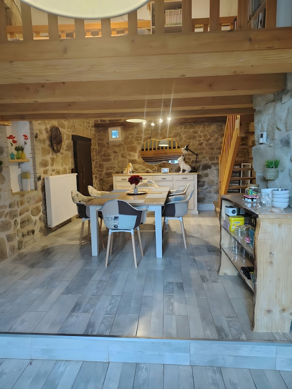 A dining area with a stone wall, wooden ceiling, and a table with chairs. - Bed and Breakfast 'Evasion' at the La Vie est Belle Breeding Farm (Boucieu-le-Roi)