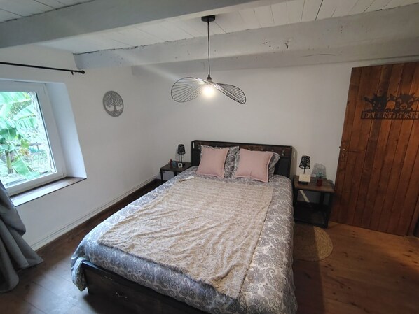 Ein Schlafzimmer mit einem Bett, einem Fenster, einer Wanddekoration und einer Holztür.
