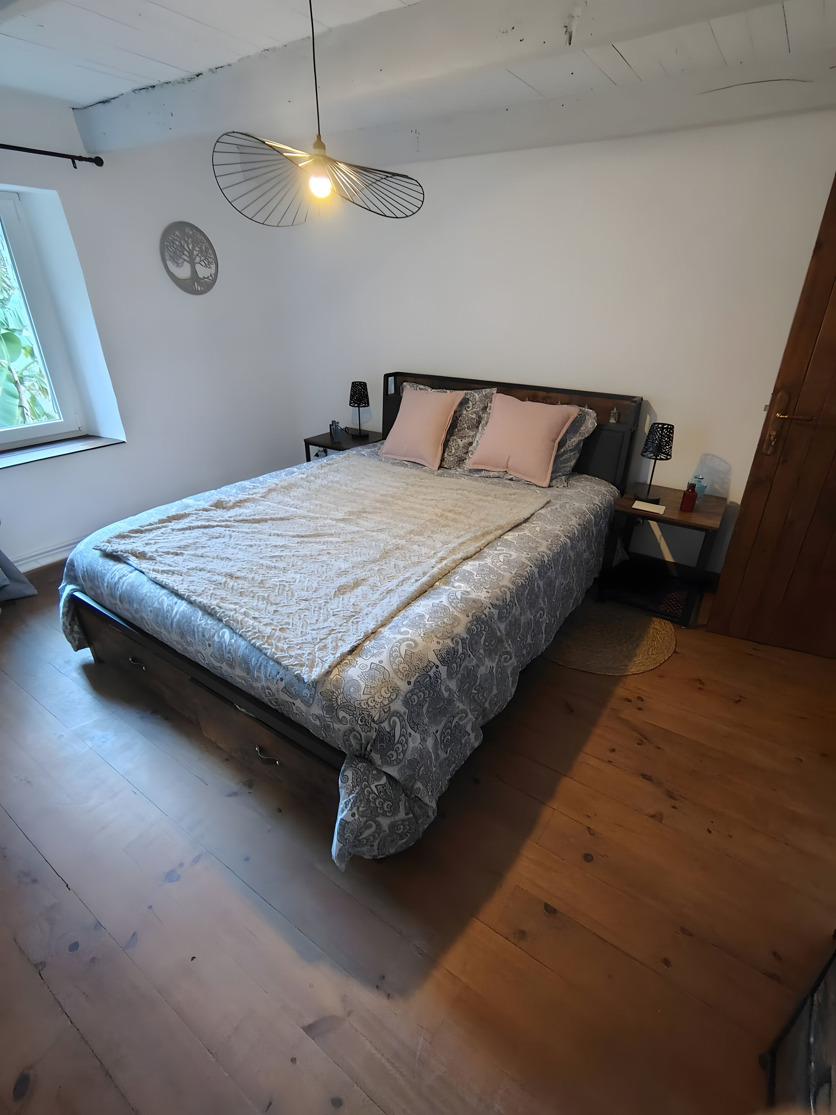 Una camera da letto con un letto, comodini, una finestra e una ventola a soffitto.