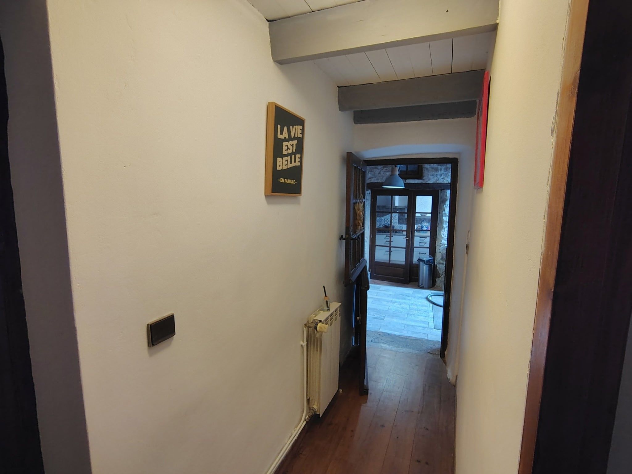 Un couloir étroit avec un radiateur et une porte donnant sur un espace extérieur.