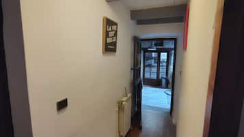 Un couloir étroit avec un radiateur et une porte donnant sur un espace extérieur.