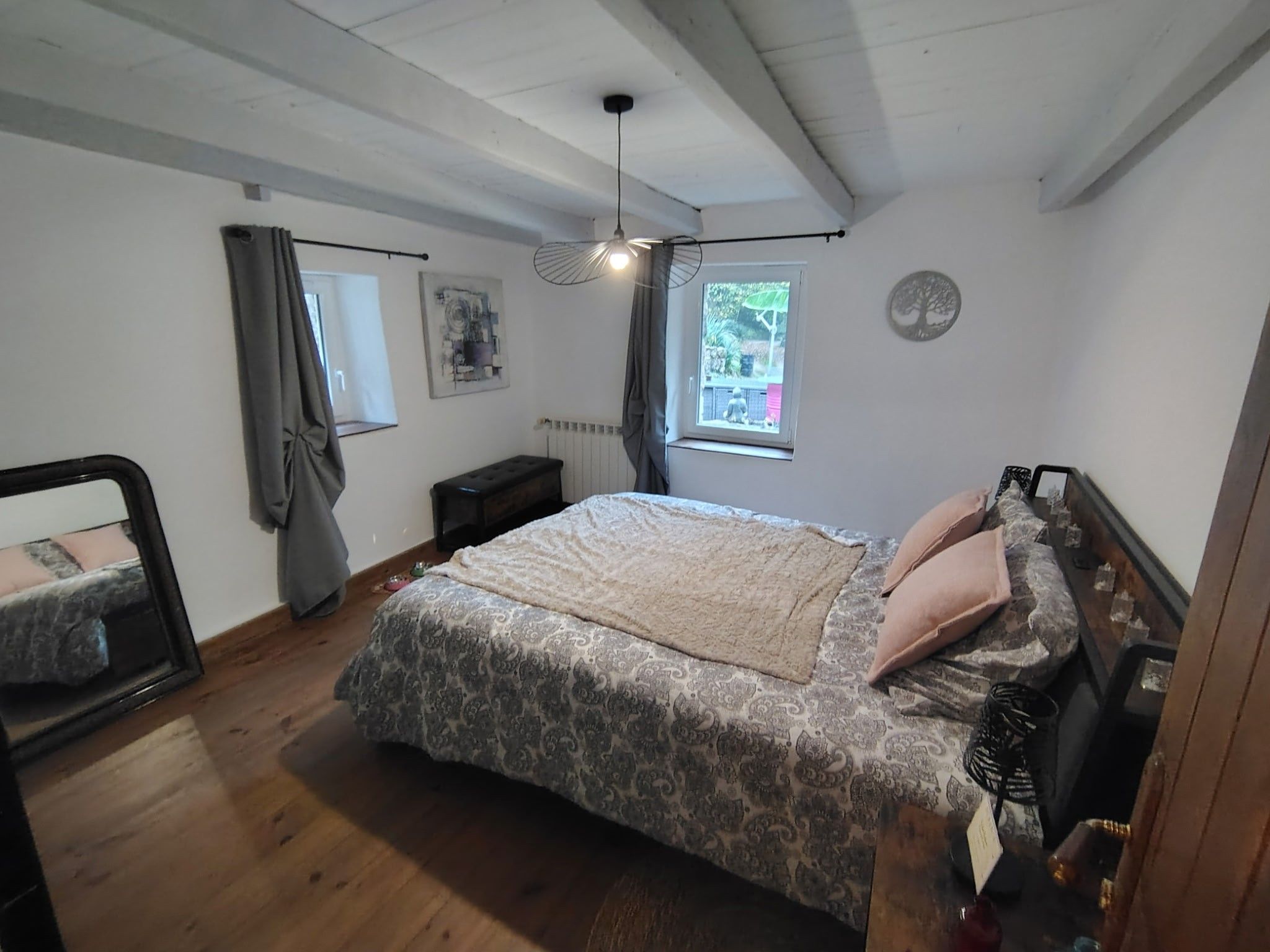 Un dormitorio con cama, radiador, ventana con vistas y ventilador de techo.