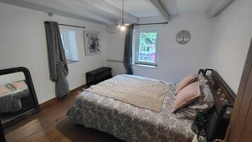 Un dormitorio con cama, radiador, ventana con vistas y ventilador de techo.