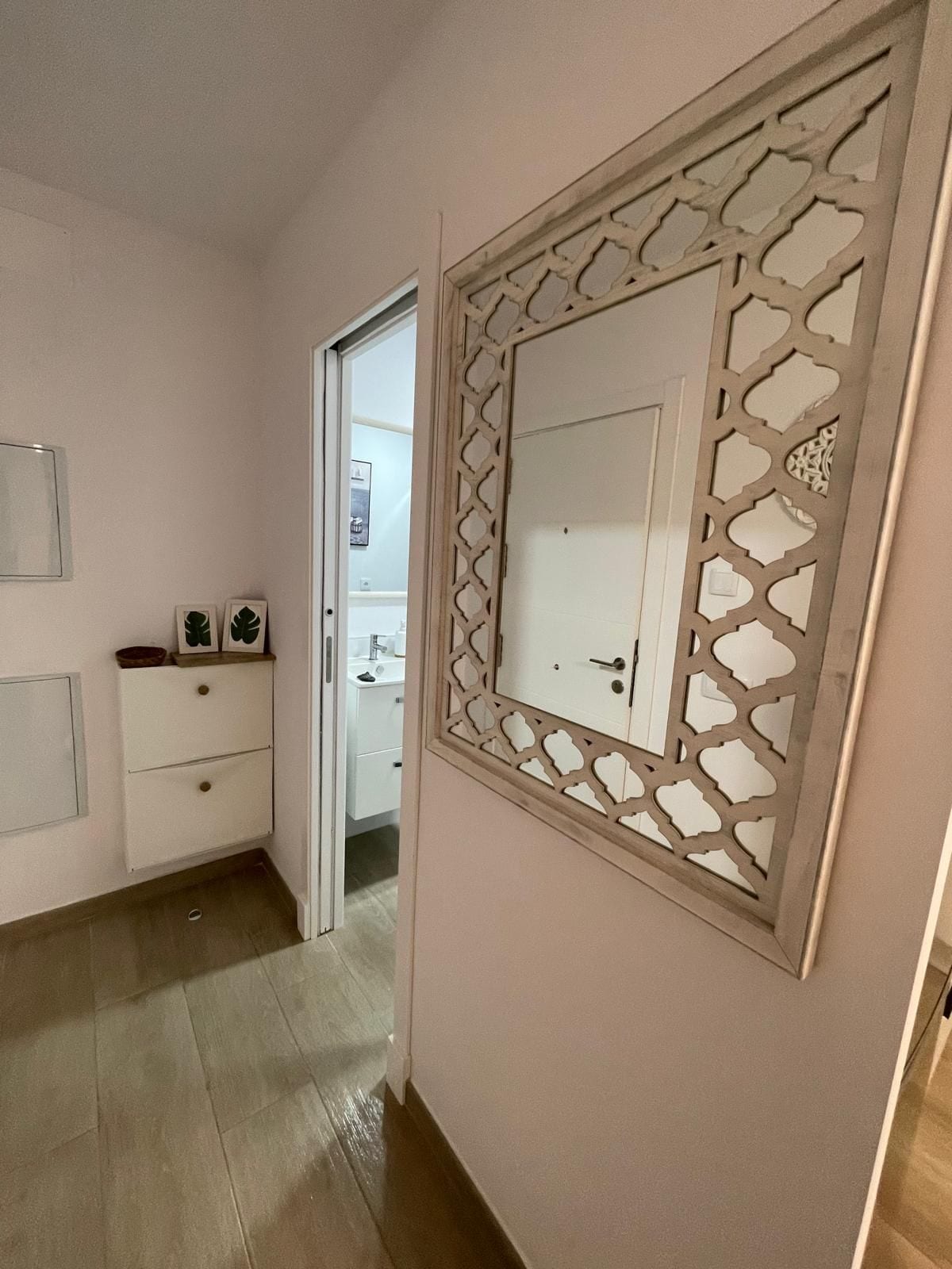 A hallway with a white door, a small cabinet with drawers, and a decorative panel with a geometric pattern.