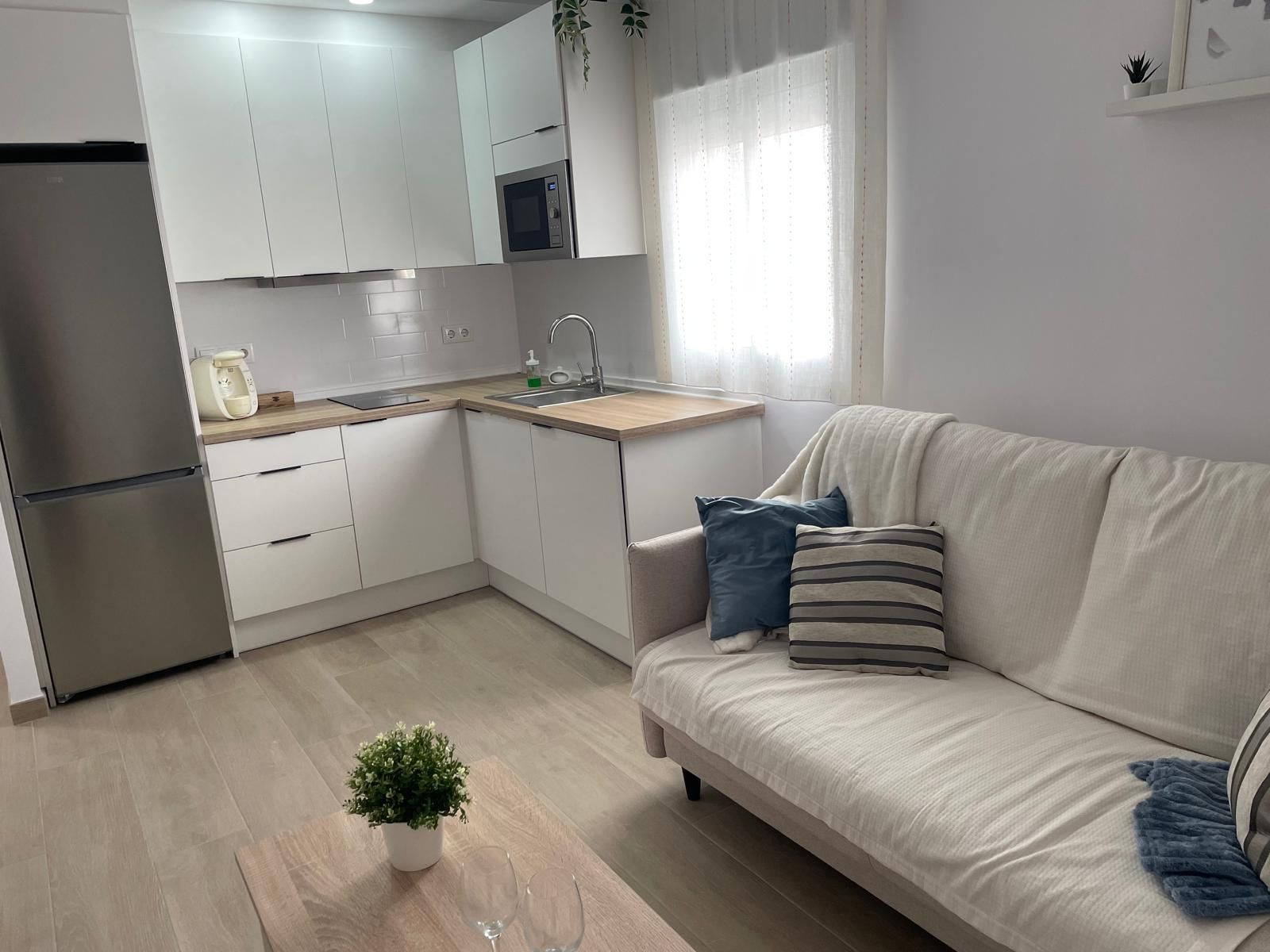 A modern kitchen with white cabinets, a built-in microwave, and a stainless steel refrigerator.