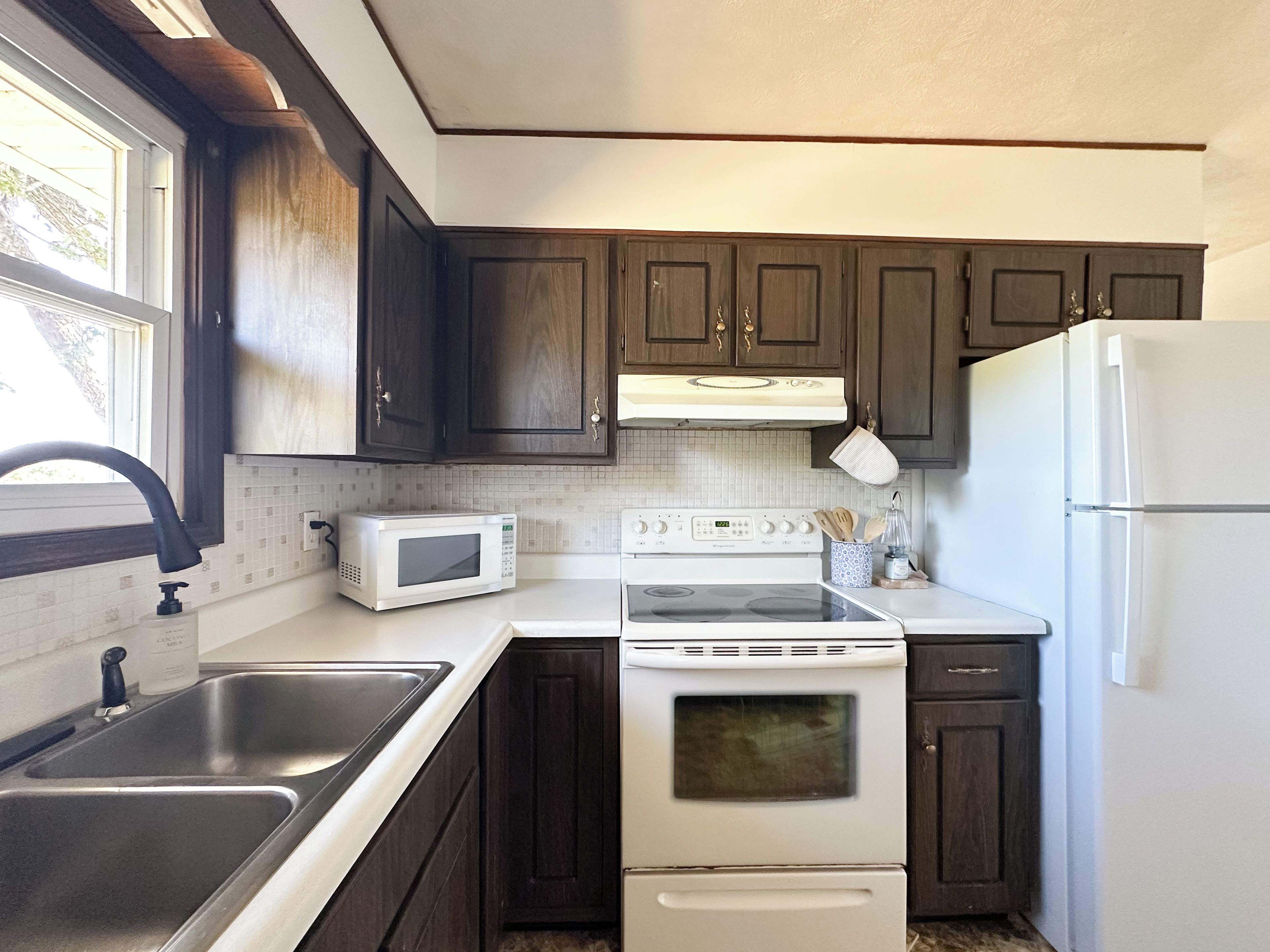Une cuisine avec des meubles de rangement en bois foncé, une cuisinière blanche, un four à micro-ondes et un réfrigérateur.