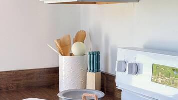 A kitchen with a stove, microwave, and a white cabinet with utensils.