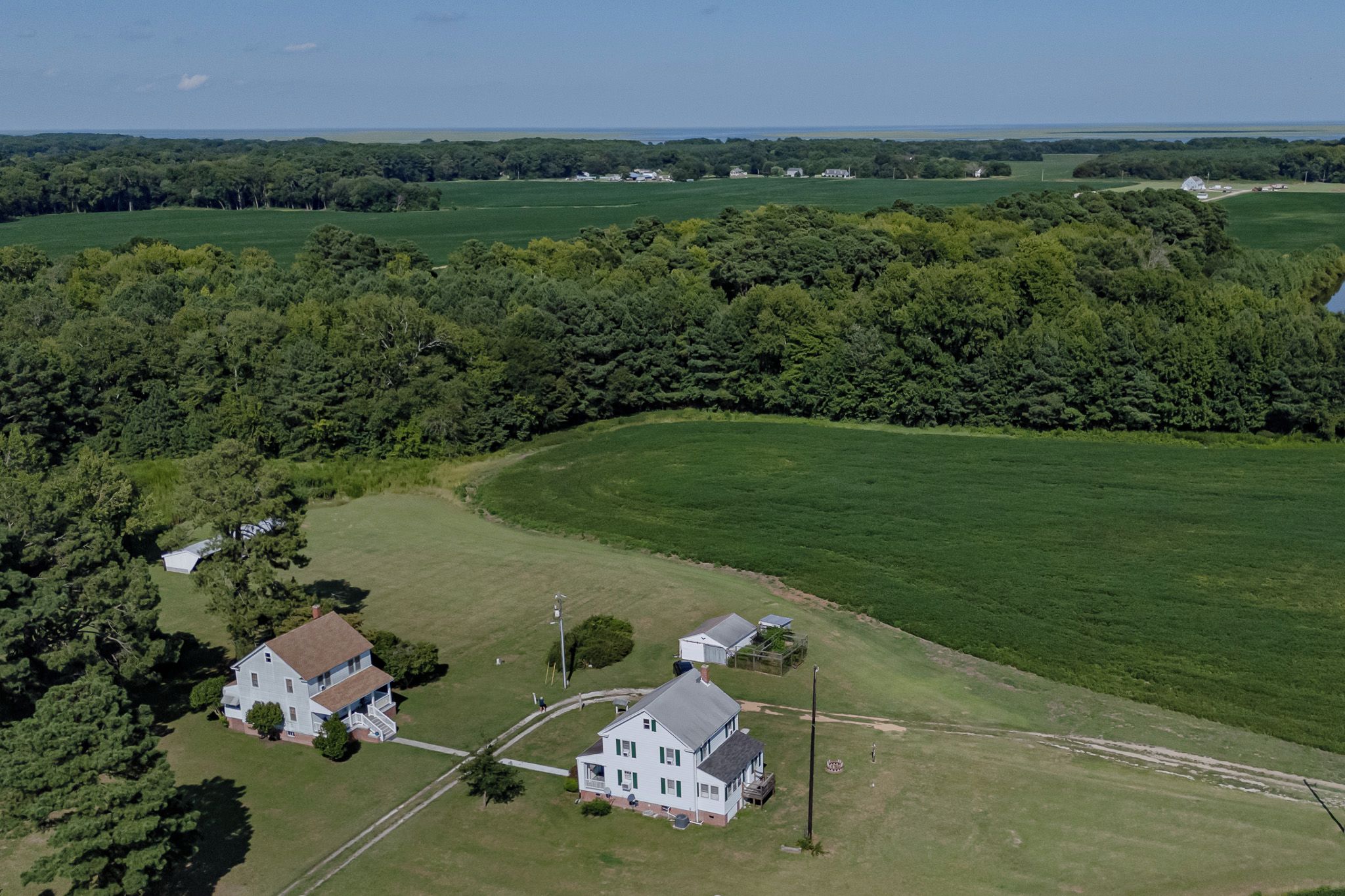 A large estate with multiple buildings, expansive green fields, and dense forested areas.