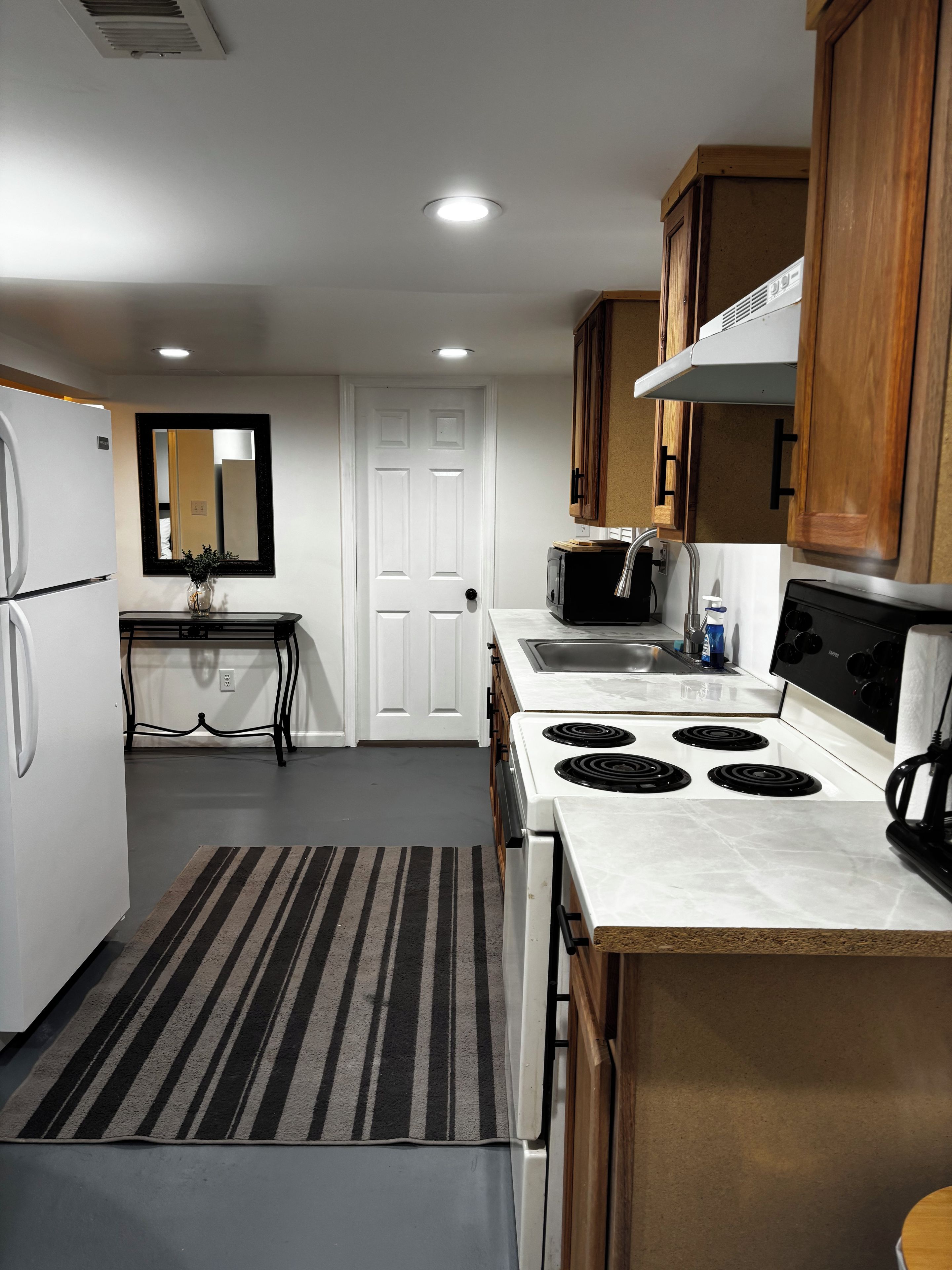 Cocina compacta equipada con refrigerador, estufa, microondas y pileta.