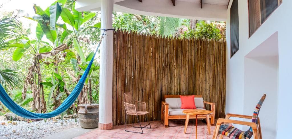 A covered outdoor seating area with a hammock, chairs, and a table.