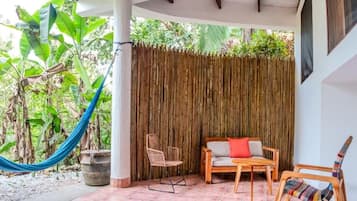 A covered outdoor seating area with a hammock, chairs, and a table.