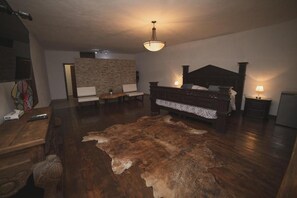 Un dormitorio con cama de madera, pared de piedra, cómoda de madera, alfombra y televisión.